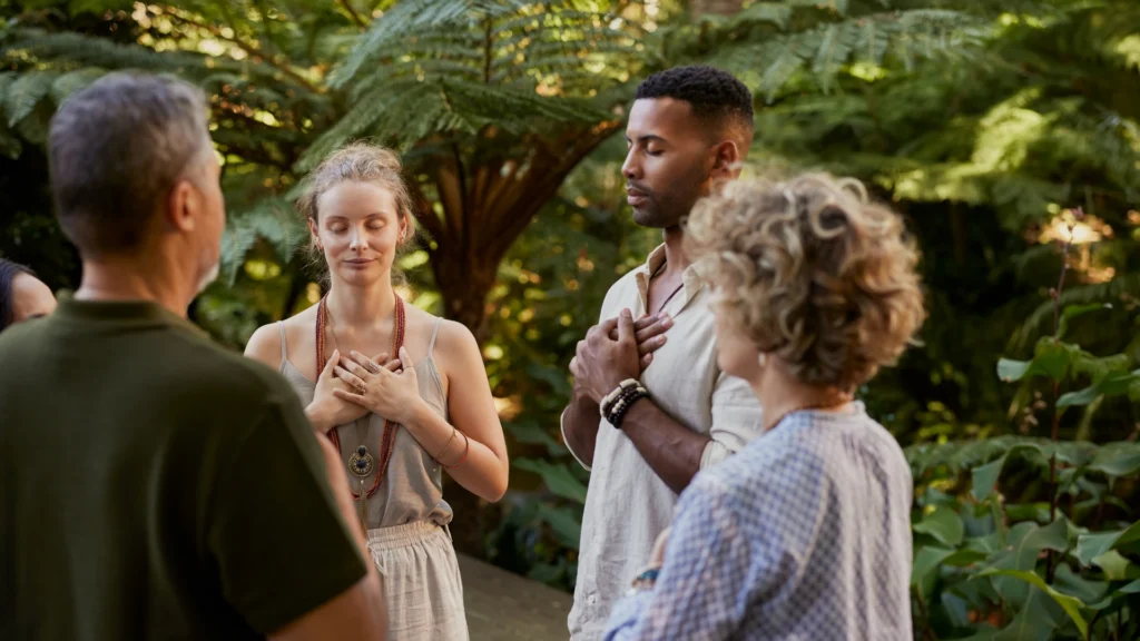 A diverse group of people standing together in a lush garden, surrounded by vibrant flowers and greenery.